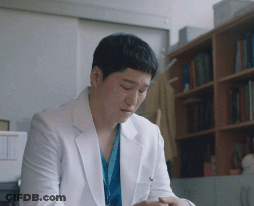 A Man In A White Lab Coat Has A Lanyard Around His Neck That Says ' Surgical ' On It GIF