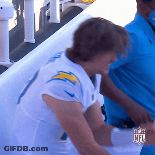 A Man In A White Nfl Jersey Stands In Front Of A White Wall GIF