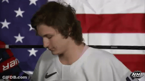 A Man In A White Nike Jersey Is Standing In Front Of An American Flag .. GIF