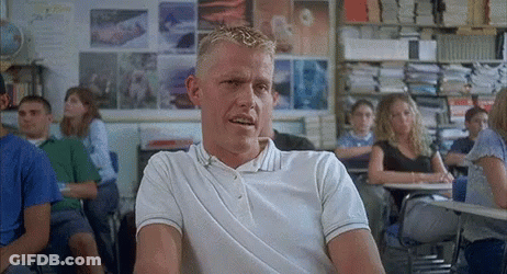A Man In A White Polo Shirt Sits In A Classroom With Other Students GIF