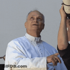 A Man In A White Robe Is Holding A Hat In His Hand GIF