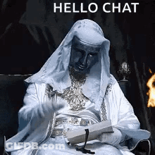 A Man In A White Robe Is Sitting In A Chair Holding A Piece Of Paper And A Candle . GIF