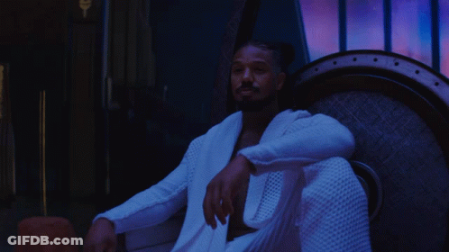 A Man In A White Robe Is Sitting In A Chair With The Words Lil ' Cousin Below Him GIF
