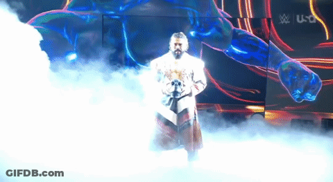 A Man In A White Robe Is Standing In A Foggy Room In Front Of A Large Screen . GIF