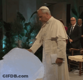 A Man In A White Robe Is Standing In Front Of A White Sphere GIF