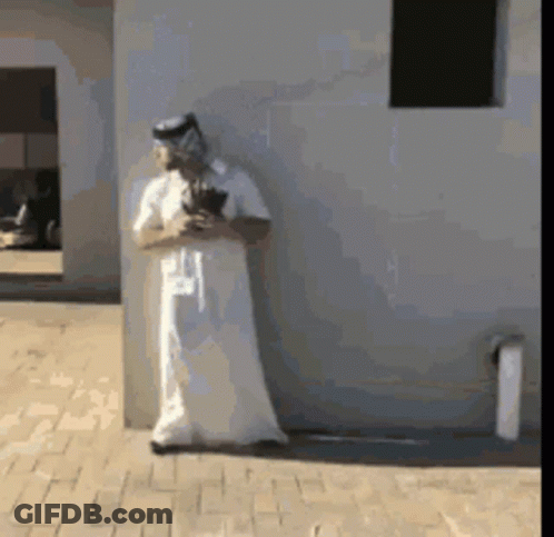 A Man In A White Robe Is Standing Next To A Wall GIF