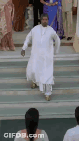 A Man In A White Robe Is Walking Down Stairs While A Woman Watches . GIF