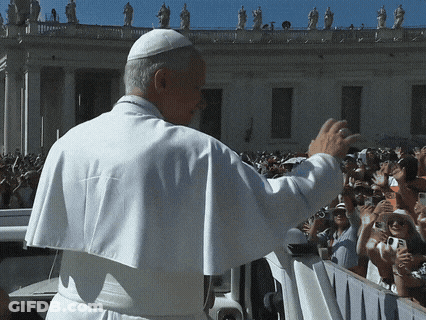 A Man In A White Robe Waves To A Crowd Of People GIF