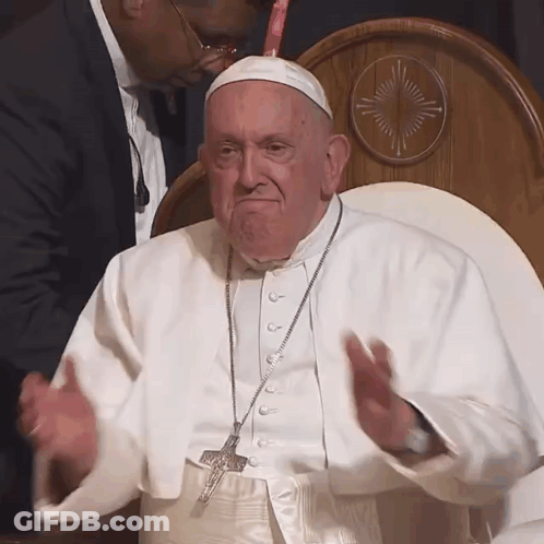 A Man In A White Robe With A Cross Necklace GIF