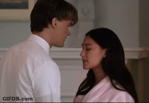 A Man In A White Shirt And A Woman In A Pink Robe Are Looking Into Each Other 'S Eyes GIF