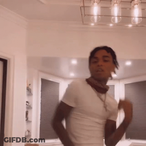 A Man In A White Shirt And Bandana Is Dancing In A Living Room . GIF
