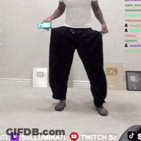 A Man In A White Shirt And Black Pants Is Holding A Cell Phone In His Hands GIF