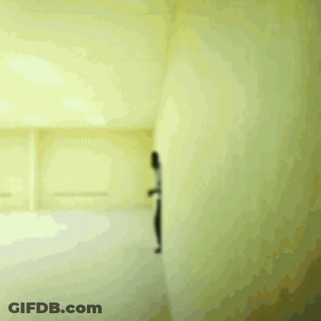 A Man In A White Shirt And Black Pants Is Running In A Room GIF