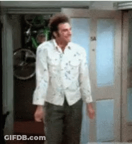 A Man In A White Shirt And Black Pants Is Standing In A Doorway . GIF