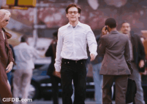 A Man In A White Shirt And Black Pants Walks Down A Street GIF