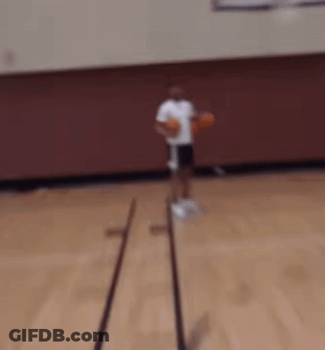 A Man In A White Shirt And Black Shorts Is Holding Two Basketballs In His Hands GIF