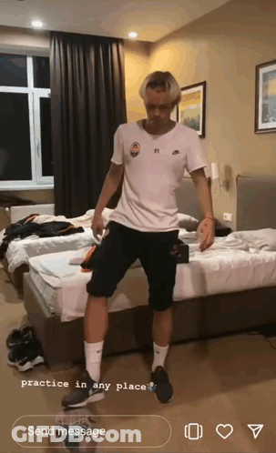 A Man In A White Shirt And Black Shorts Is Practicing In A Bedroom GIF