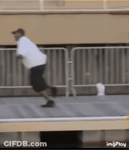 A Man In A White Shirt And Black Shorts Is Running On A Sidewalk . GIF