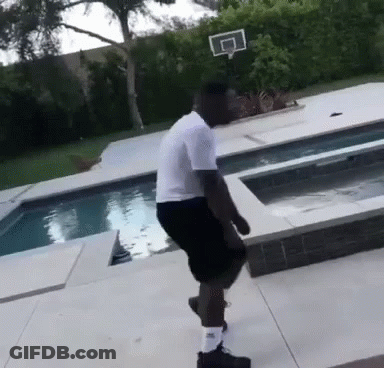 A Man In A White Shirt And Black Shorts Is Standing Next To A Swimming Pool GIF
