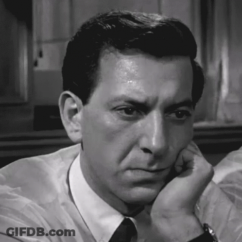 A Man In A White Shirt And Black Tie Has His Hand On His Chin GIF