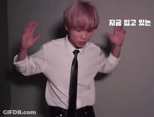 A Man In A White Shirt And Black Tie Is Dancing In Front Of A Wall With Chinese Writing On It GIF