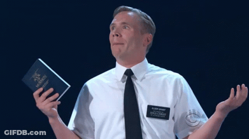 A Man In A White Shirt And Black Tie Is Holding A Book That Says " The Book Of Mormon " GIF