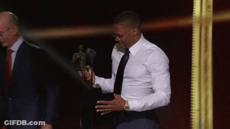 A Man In A White Shirt And Black Tie Is Holding A Trophy . GIF