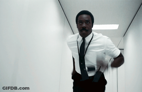 A Man In A White Shirt And Black Tie Is Running In A Hallway GIF