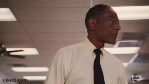 A Man In A White Shirt And Black Tie Is Standing In A Hallway With A Ceiling Fan . GIF