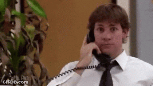 A Man In A White Shirt And Black Tie Is Talking On A Phone . GIF