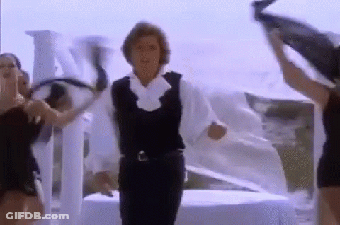 A Man In A White Shirt And Black Vest Is Dancing With Two Women . GIF