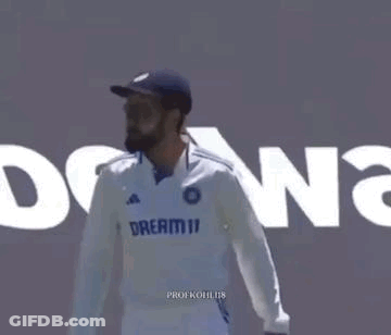 A Man In A White Shirt And Blue Hat Is Standing In Front Of A Wall With The Word Dreamii On It . GIF