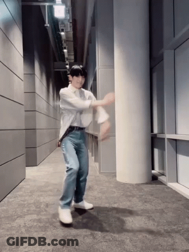 A Man In A White Shirt And Blue Jeans Is Dancing GIF
