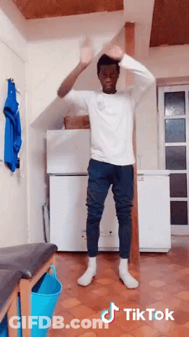 A Man In A White Shirt And Blue Pants Is Dancing In A Room With Tiktok Written On The Bottom Of The Image GIF