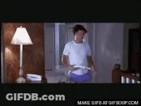 A Man In A White Shirt And Blue Shorts Is Holding A Hula Hoop In A Room .. GIF