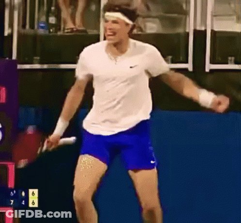 A Man In A White Shirt And Blue Shorts Is Holding A Tennis Racquet In His Hand . GIF