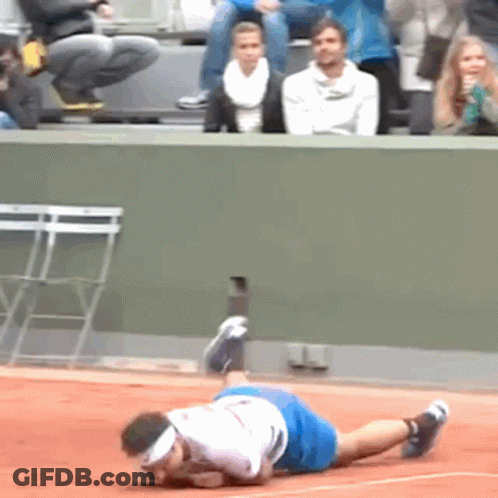 A Man In A White Shirt And Blue Shorts Is Laying On A Tennis Court GIF