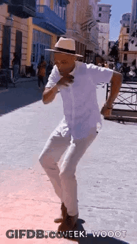 A Man In A White Shirt And Hat Is Dancing On A Street . GIF