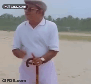A Man In A White Shirt And Hat Is Holding A Cane . GIF
