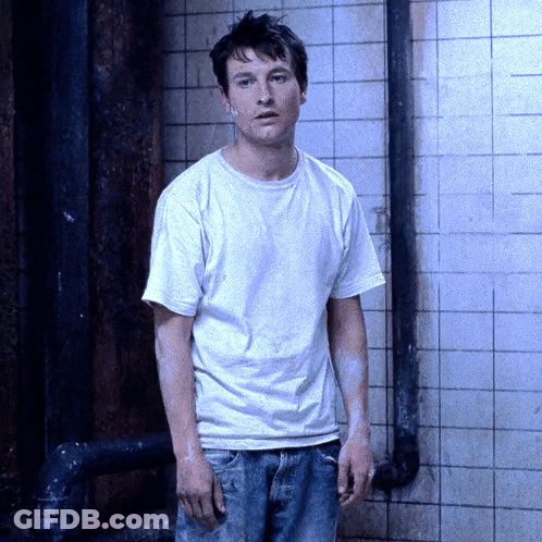 Man In White Shirt And Jeans Standing In Front Of Wall GIF