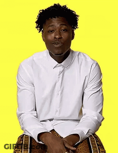 A Man In A White Shirt And Leopard Print Shorts Is Sitting On A Yellow Background And Making A Funny Face . GIF