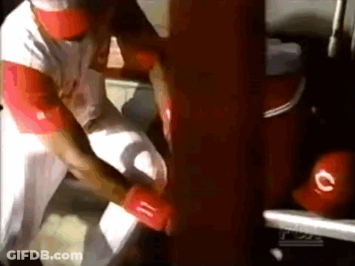 A Man In A White Shirt And Red Hat Is Holding A Red Glove With The Letter C On It GIF