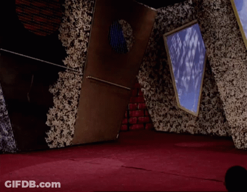 A Man In A White Shirt And Red Pants Is Jumping In The Air In A Room GIF
