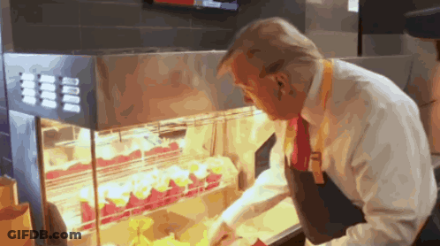 A Man In A White Shirt And Red Tie Is Looking At A Display Of Food GIF