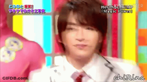 A Man In A White Shirt And Red Tie Is Talking Into A Microphone On A Colorful Background . GIF
