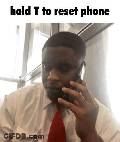 A Man In A White Shirt And Red Tie Talking On A Cell Phone With The Words Hold T To Reset Phone Above Him GIF