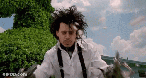 A Man In A White Shirt And Suspenders Is Holding Scissors In His Hands . GIF