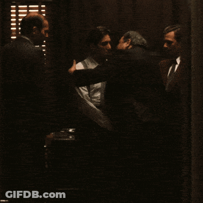 A Man In A White Shirt And Suspenders Is Shaking Hands With Another Man GIF