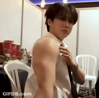 A Man In A White Shirt And Tie Is Adjusting His Tie In A Room . GIF