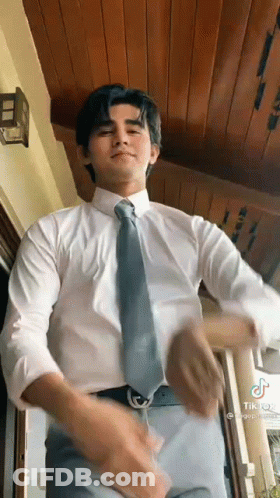A Man In A White Shirt And Tie Is Dancing In A Room . GIF